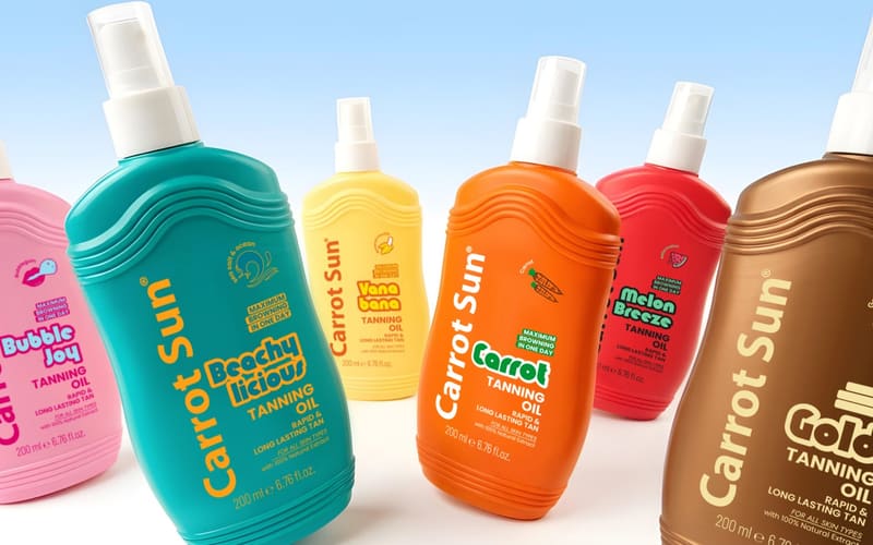 The Carrot Sun tanning oil range in pink, teal, yellow, orange, red and gold spray bottles